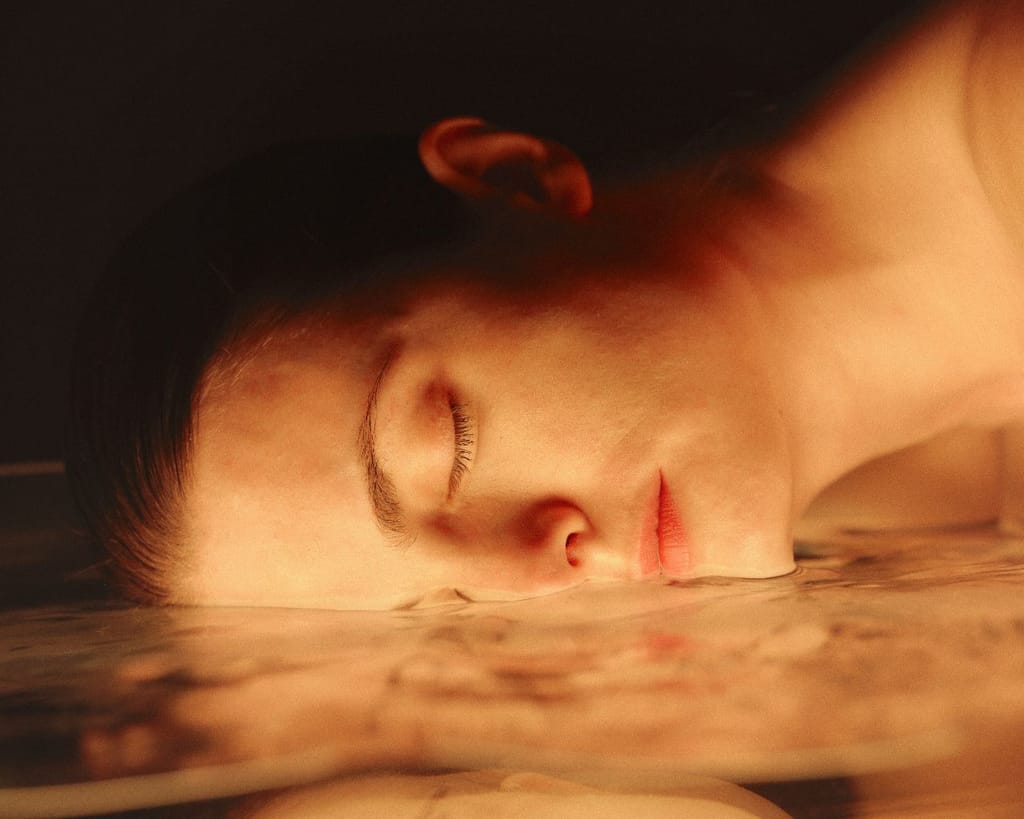 Woman resting her face on the surface of warm water