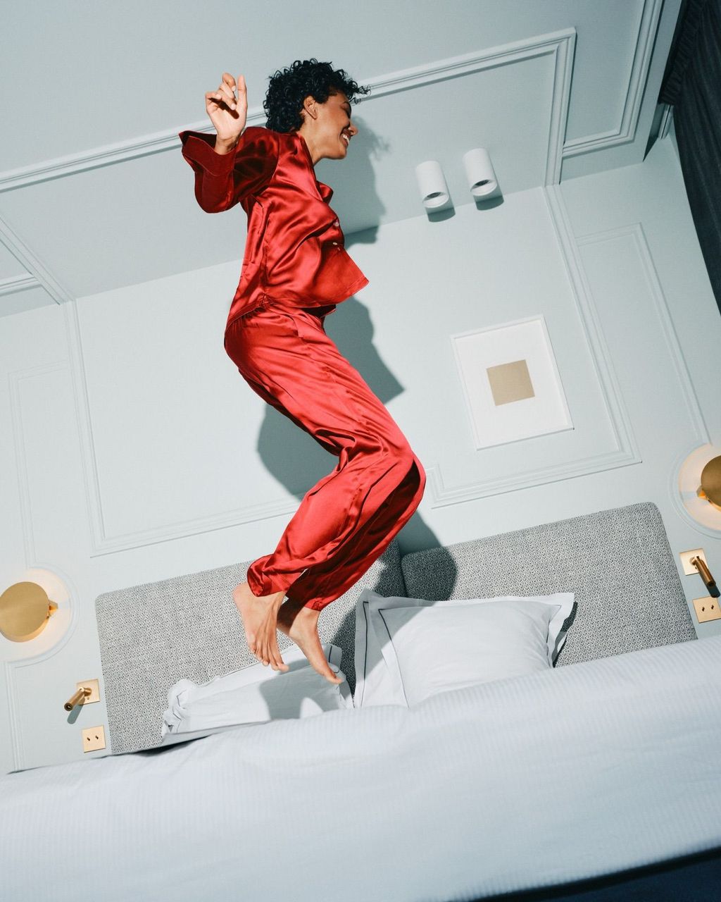 Woman in red pyjamas mid-jump on a bed
